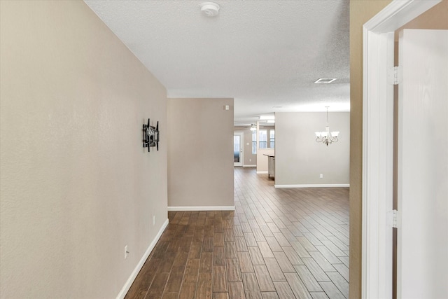 hallway with a notable chandelier and a textured ceiling