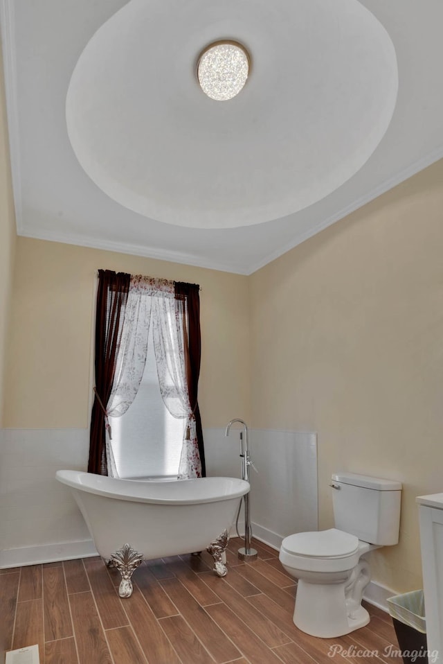 bathroom with crown molding, a tub to relax in, and toilet