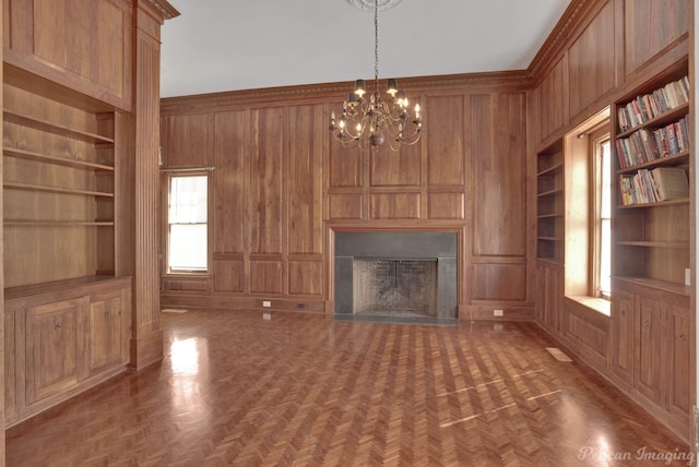 unfurnished living room featuring dark parquet flooring, wooden walls, and built in shelves