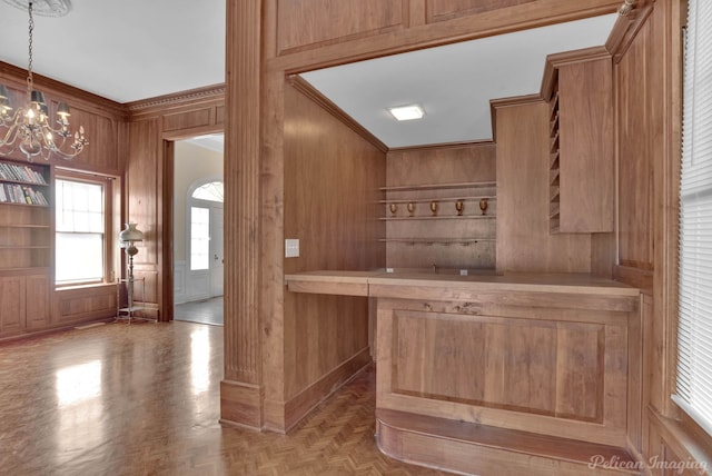 bar with wood walls, crown molding, decorative light fixtures, a notable chandelier, and light parquet floors