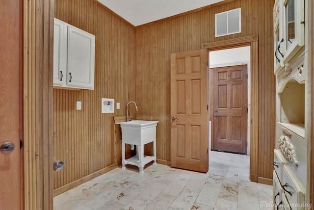 clothes washing area featuring cabinets, stacked washer / dryer, and wood walls