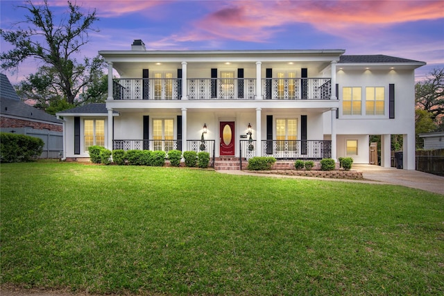 view of front of property featuring a balcony, a yard, and a porch