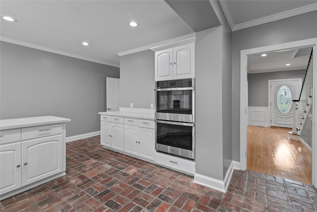 kitchen featuring stainless steel double oven, ornamental molding, and white cabinetry