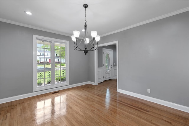 unfurnished dining area featuring hardwood / wood-style floors, an inviting chandelier, and crown molding