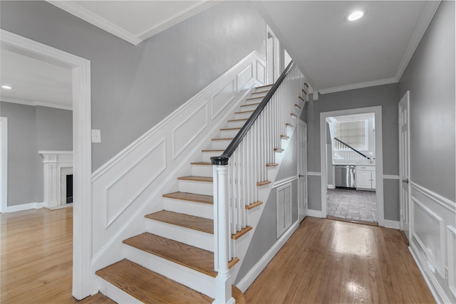 staircase with hardwood / wood-style floors and ornamental molding