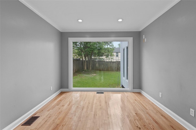 empty room with ornamental molding and light hardwood / wood-style floors