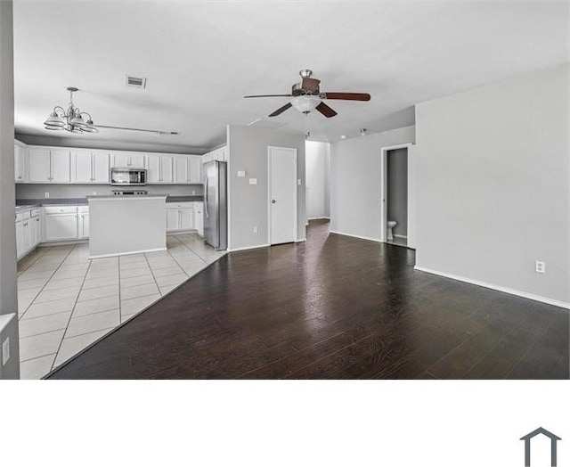 unfurnished living room featuring ceiling fan with notable chandelier and light hardwood / wood-style floors