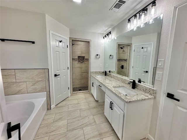 bathroom featuring a textured ceiling, separate shower and tub, and vanity