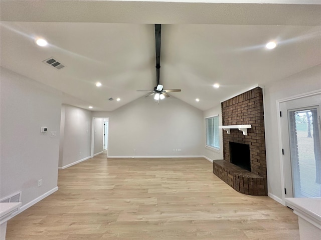 unfurnished living room featuring vaulted ceiling with beams, light hardwood / wood-style flooring, a brick fireplace, and ceiling fan