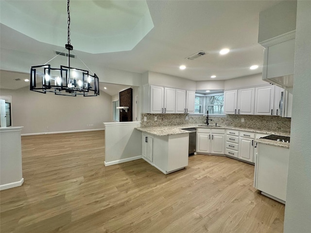 kitchen with hanging light fixtures, kitchen peninsula, sink, white cabinets, and tasteful backsplash