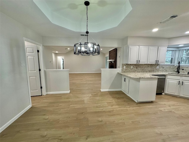 kitchen featuring sink, white cabinets, light hardwood / wood-style flooring, stainless steel dishwasher, and kitchen peninsula