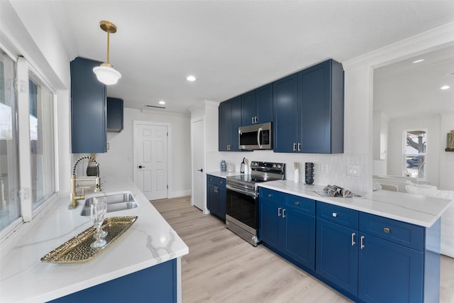 kitchen featuring kitchen peninsula, decorative light fixtures, stainless steel appliances, blue cabinetry, and sink