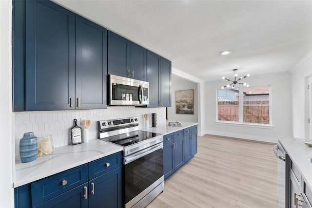 kitchen featuring stainless steel appliances, decorative backsplash, blue cabinetry, and light hardwood / wood-style floors