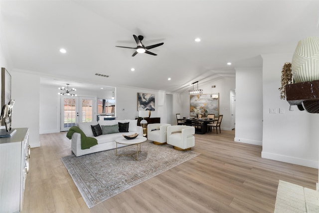 living room featuring light hardwood / wood-style floors, french doors, vaulted ceiling, and ceiling fan with notable chandelier