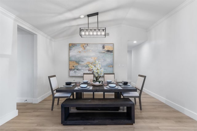 dining space featuring light hardwood / wood-style floors, an inviting chandelier, vaulted ceiling, and crown molding