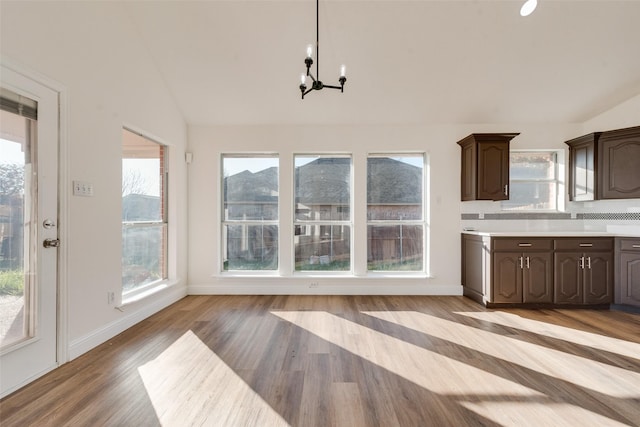 kitchen featuring a chandelier, vaulted ceiling, dark brown cabinets, and light hardwood / wood-style flooring