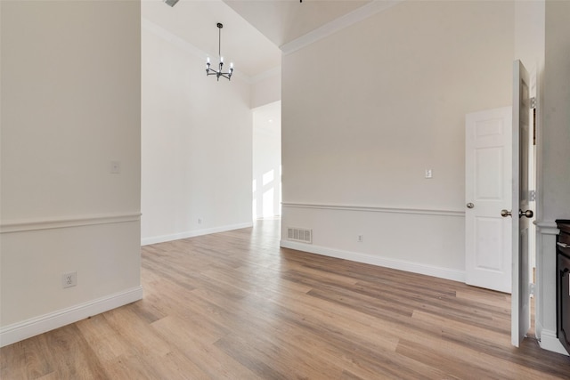 unfurnished room with ornamental molding, light wood-type flooring, and an inviting chandelier