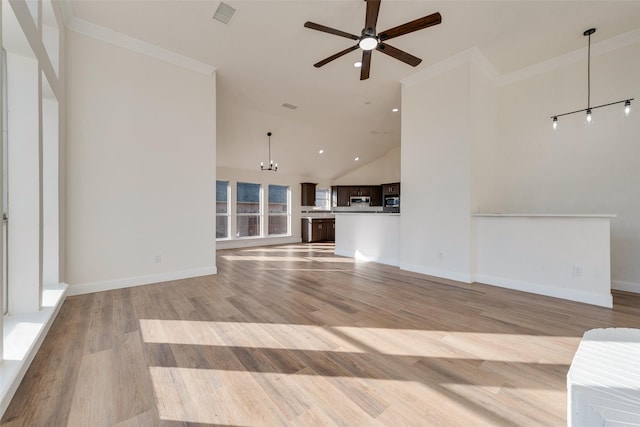 unfurnished living room with ceiling fan with notable chandelier, a towering ceiling, ornamental molding, and light hardwood / wood-style flooring