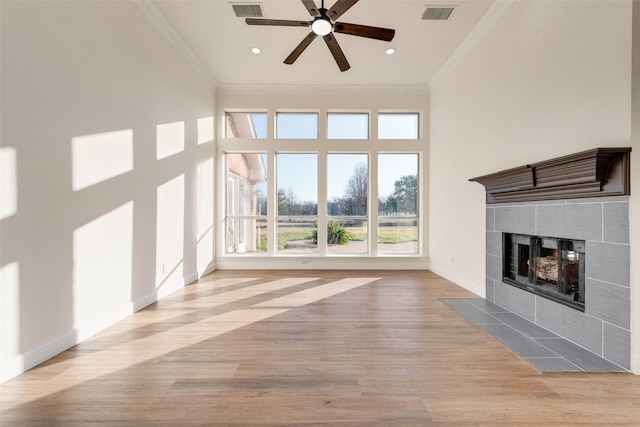 unfurnished living room with a tiled fireplace, ceiling fan, light hardwood / wood-style flooring, and ornamental molding