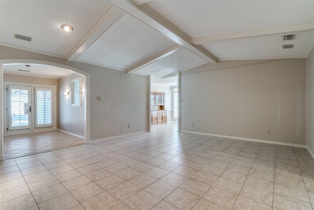 unfurnished room featuring arched walkways, light tile patterned floors, a textured ceiling, and visible vents