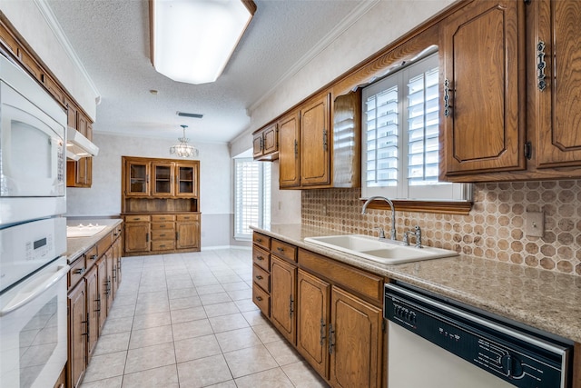 kitchen with dishwasher, white oven, hanging light fixtures, light countertops, and a sink