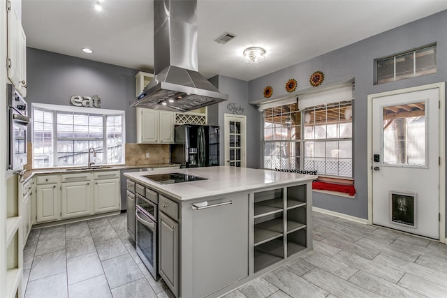 kitchen with a center island, black appliances, white cabinetry, island exhaust hood, and sink