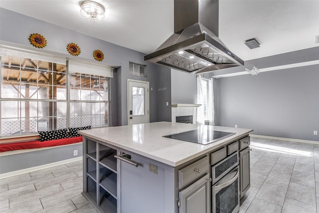 kitchen with black electric stovetop, oven, gray cabinetry, open shelves, and island exhaust hood