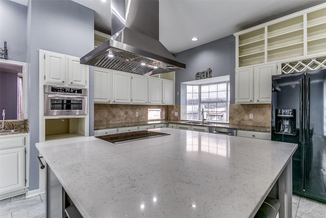 kitchen with black appliances, island exhaust hood, white cabinetry, and a center island