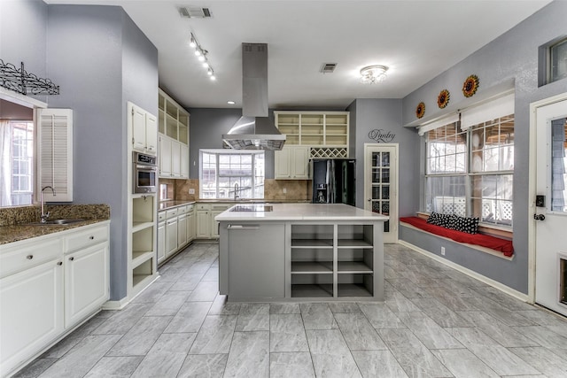 kitchen featuring black fridge with ice dispenser, oven, island exhaust hood, open shelves, and a sink