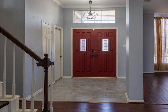 foyer entrance featuring a healthy amount of sunlight, stairs, crown molding, and wood finished floors