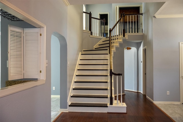 stairway featuring baseboards, arched walkways, and wood finished floors