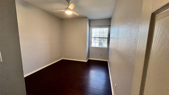 spare room with dark wood-style floors, ceiling fan, a textured wall, and baseboards