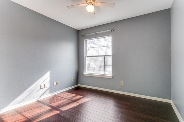 empty room featuring a ceiling fan, dark wood finished floors, and baseboards