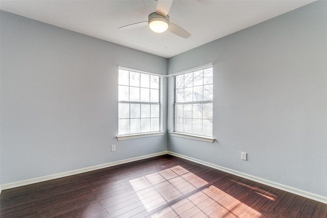 spare room with ceiling fan, dark wood-type flooring, and baseboards