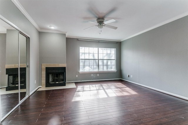 unfurnished living room with ceiling fan, ornamental molding, dark wood-style flooring, and a fireplace with flush hearth