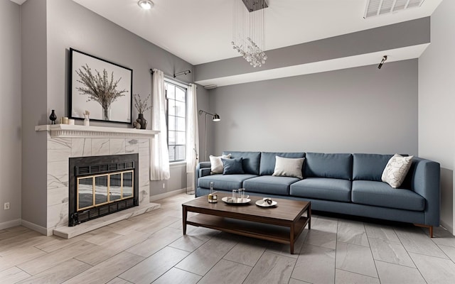 living area with wood finished floors, a high end fireplace, visible vents, and baseboards