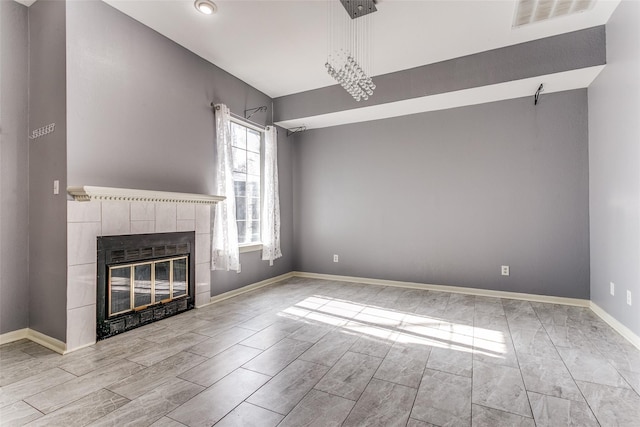 unfurnished living room featuring wood finished floors, a tile fireplace, visible vents, and baseboards