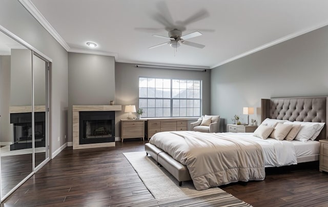 bedroom with ceiling fan, a fireplace, ornamental molding, and dark wood finished floors