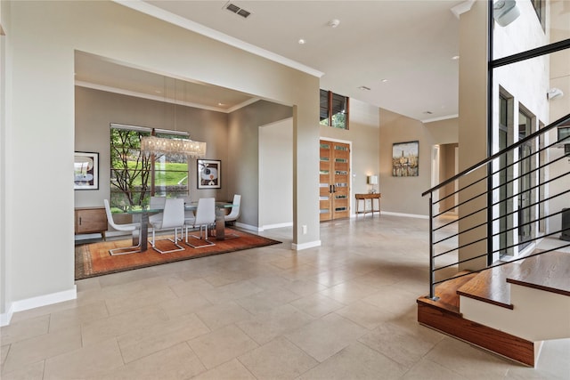 entrance foyer featuring ornamental molding, an inviting chandelier, and a towering ceiling