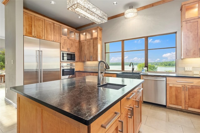 kitchen with a center island with sink, built in appliances, light tile patterned floors, a notable chandelier, and sink