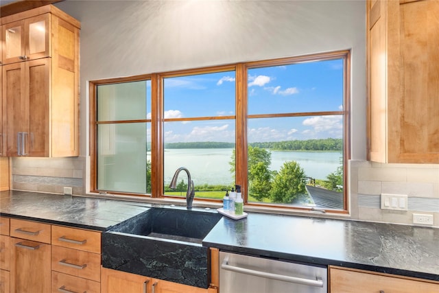 kitchen featuring sink, a water view, stainless steel dishwasher, and decorative backsplash