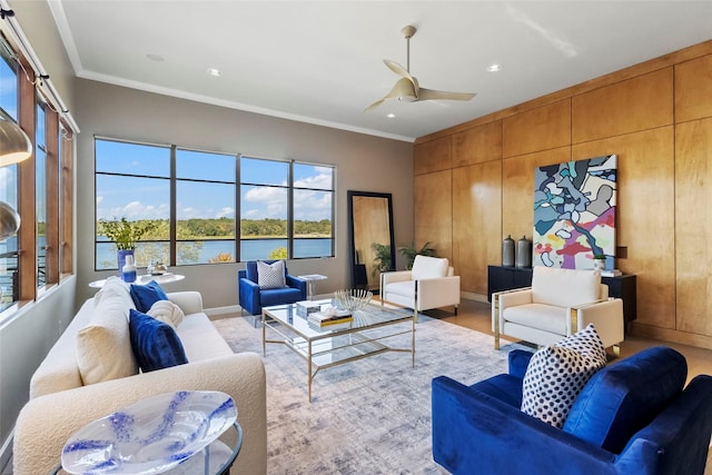 living room featuring ornamental molding, ceiling fan, light hardwood / wood-style floors, and a water view