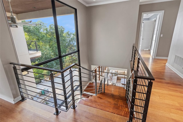 stairway with hardwood / wood-style floors, a wealth of natural light, and crown molding