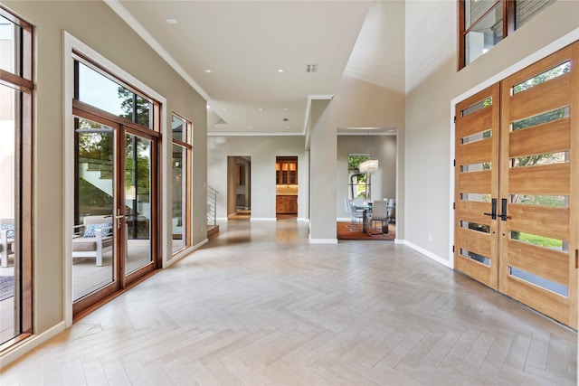 entryway with light parquet flooring, french doors, and crown molding