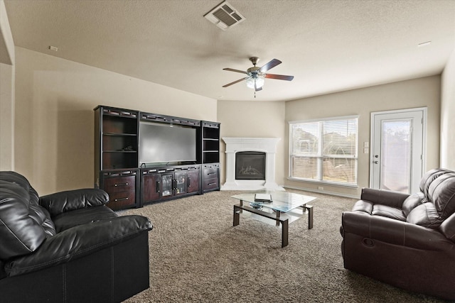 carpeted living room with ceiling fan and a textured ceiling