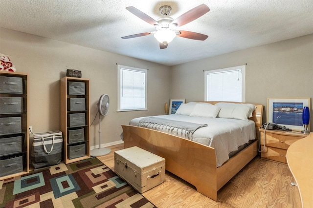 bedroom featuring ceiling fan, light hardwood / wood-style flooring, and a textured ceiling