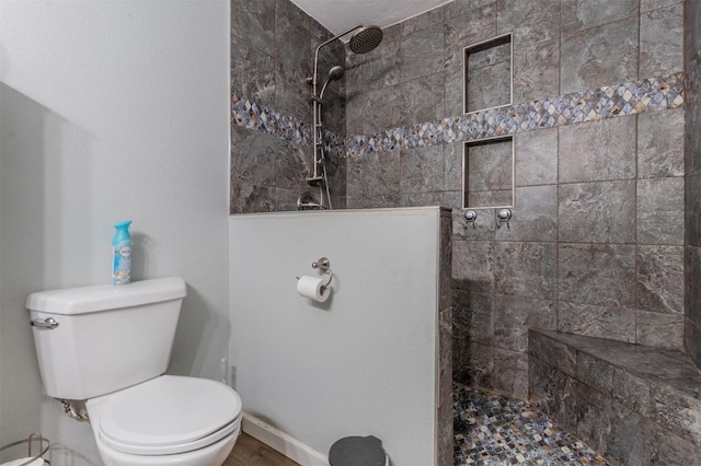 bathroom with a tile shower and toilet