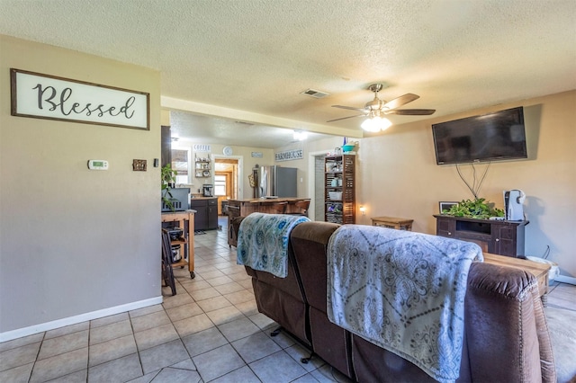 living room featuring a textured ceiling, ceiling fan, and tile patterned floors