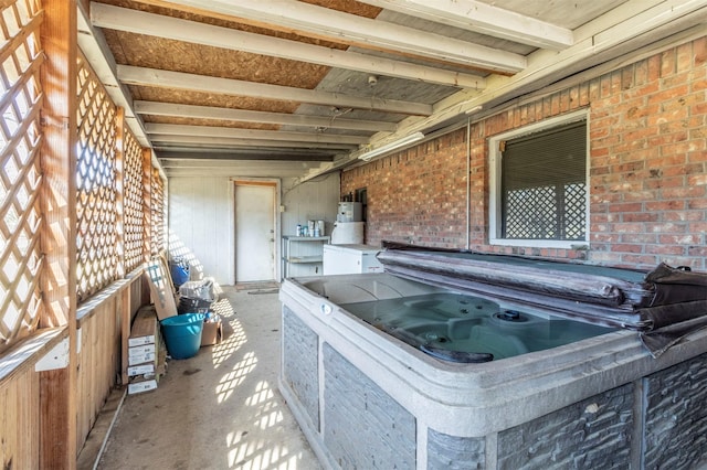 interior space featuring brick wall, a hot tub, water heater, and beamed ceiling