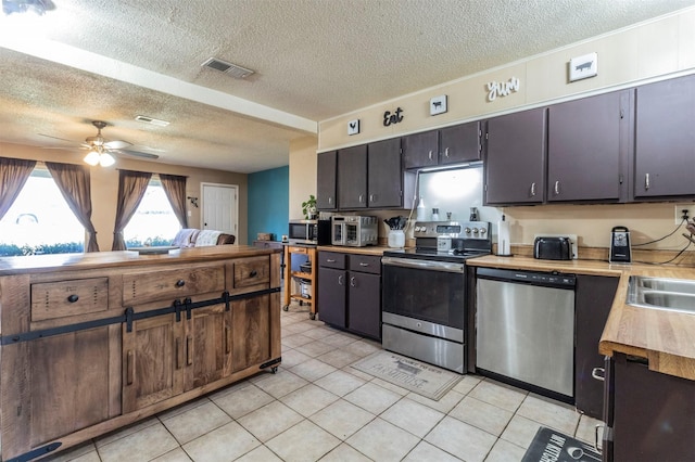 kitchen featuring a textured ceiling, appliances with stainless steel finishes, ceiling fan, and dark brown cabinetry